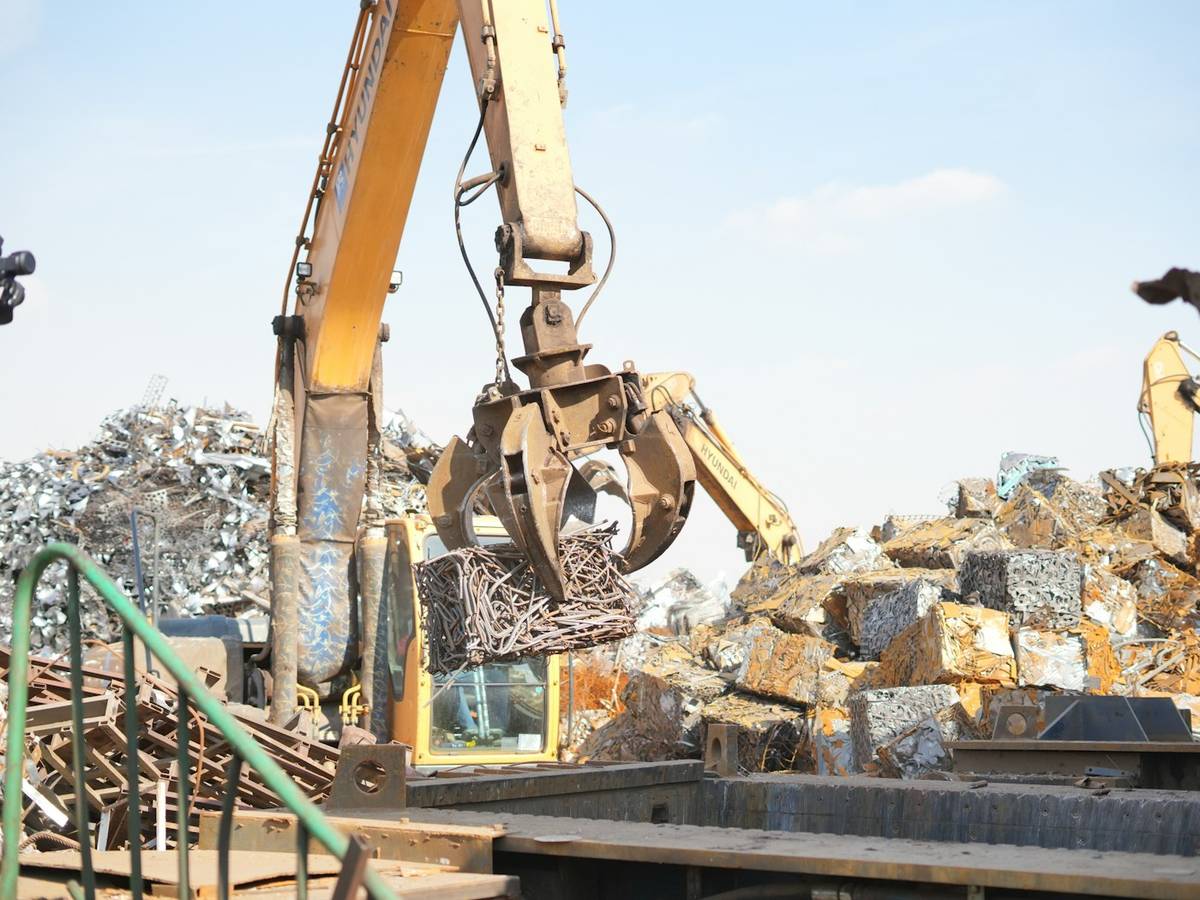 Grab crane sorting metal above baled scrap at a recycling yard